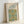 May include: Framed botanical art print featuring William Morris-style decorative pattern with blue and golden yellow flowers, green vines and leaves on cream background. Light wood frame displayed against white wall, showing vintage floral wallpaper design with intricate Arts and Crafts movement styling from 1873 Smithsonian collection.