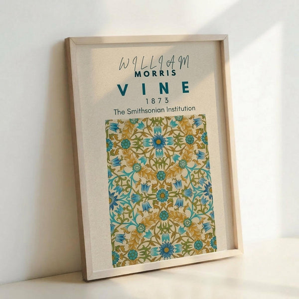 May include: Framed botanical art print featuring William Morris-style decorative pattern with blue and golden yellow flowers, green vines and leaves on cream background. Light wood frame displayed against white wall, showing vintage floral wallpaper design with intricate Arts and Crafts movement styling from 1873 Smithsonian collection.