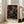 May include: Framed art print with colorful dot pattern on black background featuring swirling circles, spirals, and geometric shapes in vibrant blues, oranges, pinks, and yellows. Text reads "YAYOI KUSAMA" with Japanese characters and "TOKYO" below. Light wood frame leaning against white wall next to beige sofa in bright room with large windows.