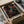 A person's hands are holding a cardboard box containing a framed poster with a colorful abstract design.