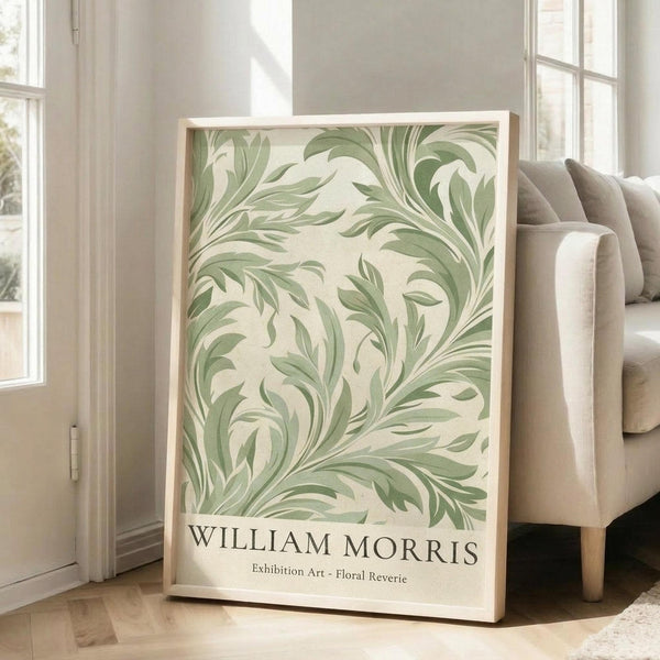 May include: Large framed botanical art print featuring flowing green leaf patterns on cream background, displayed on hardwood floor against white wall next to beige upholstered sofa with natural lighting from tall windows creating soft shadows across the bright, minimalist living room interior.