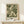May include: Framed botanical art print featuring flowing green and cream acanthus leaf pattern in William Morris style, displayed on light wood console table with small white wrapped gift beside it, against neutral wall in minimalist room setting
