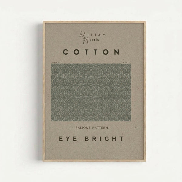 Framed poster with beige background displaying "William Morris" and "COTTON" text above a square green botanical pattern sample dated 1882-1883, with "FAMOUS PATTERN" and "EYE BRIGHT" text below. Light wood frame against white wall.