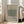 May include: Framed poster with beige background featuring William Morris Cotton pattern from 1882-1883. Green textured square pattern sample labeled "Eye Bright" displayed in light wood frame, leaning against white wall next to beige upholstered chair in bright, sunlit room with hardwood floors.