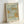 May include: Framed vintage-style botanical art print with ornate acanthus leaves and flowering vines in sage green, cream, and golden orange colors. Features decorative Arts and Crafts movement design with "St James The MET Museum 1881" and "William Morris" text. Natural wood frame displayed against white wall, showing detailed flowing organic patterns and elegant typography on textured paper background.