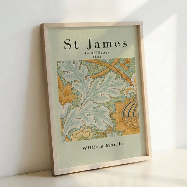 May include: Framed vintage-style botanical art print with ornate acanthus leaves and flowering vines in sage green, cream, and golden orange colors. Features decorative Arts and Crafts movement design with "St James The MET Museum 1881" and "William Morris" text. Natural wood frame displayed against white wall, showing detailed flowing organic patterns and elegant typography on textured paper background.