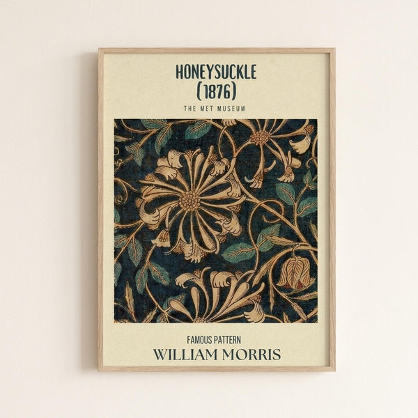 May include: Framed botanical art print hanging on white wall featuring intricate William Morris honeysuckle pattern from 1876. Design shows flowing golden honeysuckle flowers and green leaves on dark blue background in ornate Victorian style. Light wood frame with cream matting displays museum-style formatting with black text above and below the decorative floral motif.
