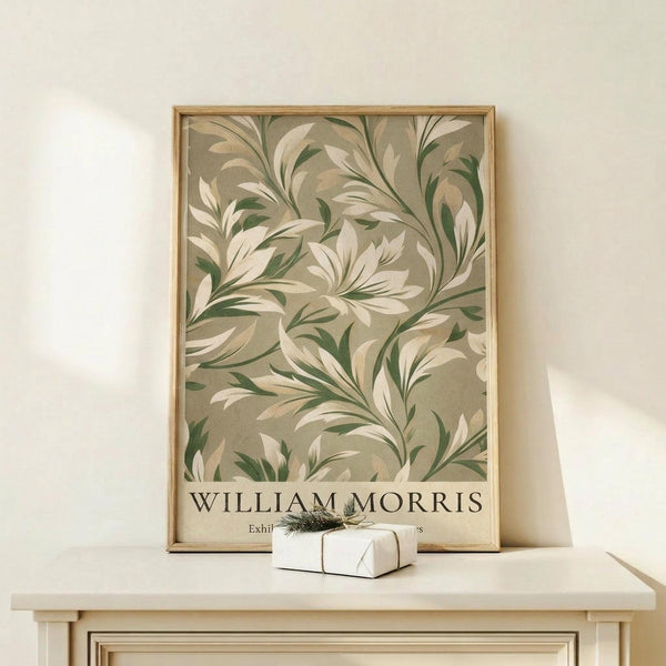 May include: Framed botanical art print featuring flowing green and cream foliage pattern on beige background, displayed on light wood console table next to small wrapped gift with twine and greenery sprig against cream wall