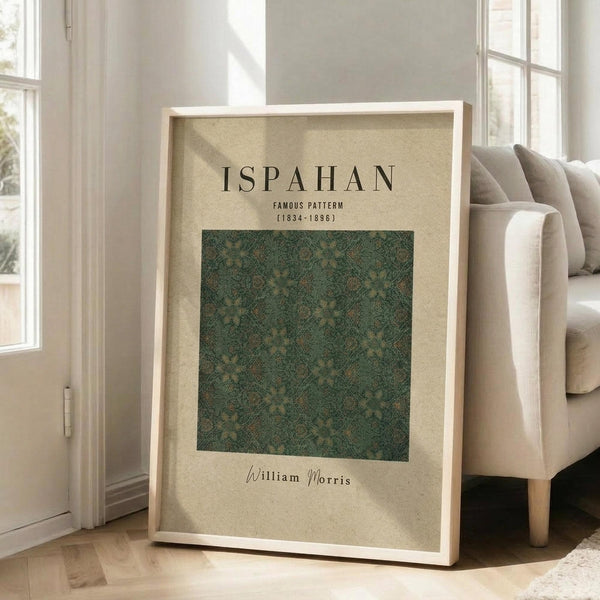 May include: Framed vintage-style poster with cream background featuring green ornate paisley pattern design, displayed leaning against white wall next to beige upholstered chair in bright living room with large windows and wooden floors