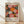 May include: Framed poster with colorful circular and radial patterns in pink, orange, yellow, and black with white dots, displayed against white wall on light wood floor. Shows "YAYOI KUSAMA" text and "28. APRIL - 14. MAI 1984" exhibition dates, with "MUSÉE d'ART MODERNE DE LA VILLE DE PARIS" at bottom. Natural wood frame, soft lighting creates diagonal shadows across white wall.