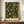 May include: Framed botanical art print featuring intricate fruit and floral pattern with yellow citrus, orange peaches, red berries, and green foliage on black background, displayed on wooden sideboard beside white ceramic vase and books in elegant room with cream walls and white molding.