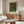 May include: Framed botanical art print featuring William Morris fruit pattern with green leaves, yellow lemons, peaches and small red flowers on dark background, displayed above walnut credenza in modern living room with white curved chair, glass coffee table, and floor lamp