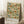 May include: Framed botanical poster print featuring blue birds among orange flowers and green foliage in a decorative trellis pattern, displayed against white paneled walls near a wooden side table with coffee cup and cozy throw blanket on carpeted floor.