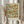 May include: Hands holding a framed botanical art print featuring blue birds, orange flowers, and green vines in William Morris style against a trellis pattern. Person wears cream ruffled sleeves, holds dried pampas grass, standing by white curtained window in soft natural lighting.