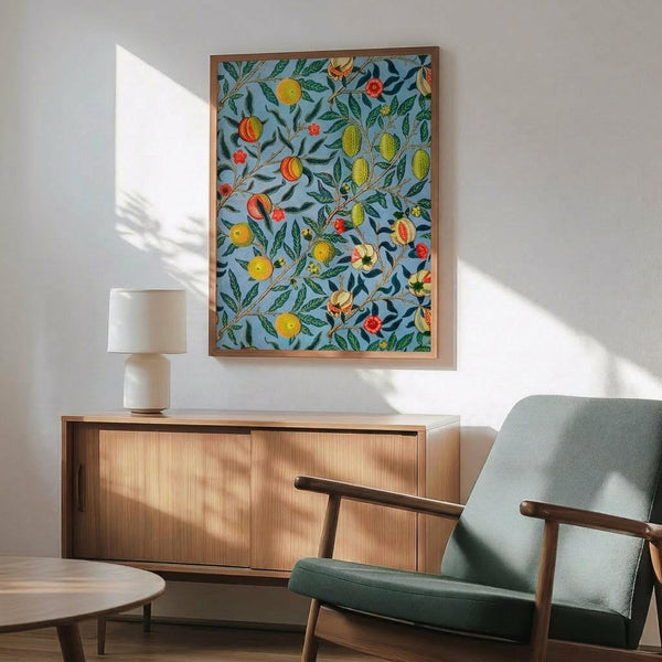 May include: Framed botanical art print with blue background featuring colorful fruits, flowers, and green leaves in William Morris style, displayed above wooden sideboard with table lamp in modern living room setting with mid-century green armchair and round coffee table