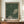 May include: Framed poster with black and cream polka dot pattern creating an abstract design, displayed on wooden sideboard next to white ceramic vase and books. Wood frame against white paneled wall in modern interior setting.