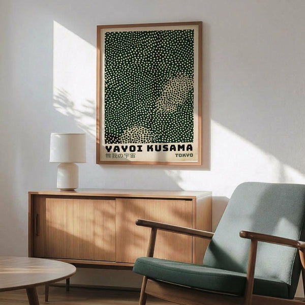a living room with a framed poster of a green and white pattern hanging on the wall above a wooden cabinet. The poster is titled "Vavoi Kusama" and "T Tokyo", suggesting it is a piece of artwork or design related to the artist Vavoi Kusama and Tokyo. The room has a wooden floor, a green armchair, and a wooden coffee table, creating a cozy and inviting atmosphere.