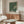 a modern living room with a large abstract painting on the wall, a wooden cabinet, a white sofa, and a glass coffee table.