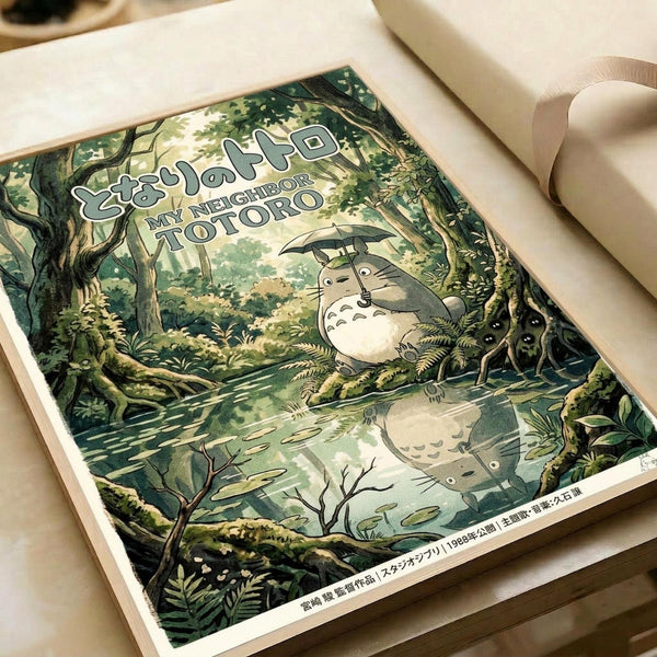An illustrated poster featuring Totoro, the beloved forest spirit character, standing in a lush green woodland setting while holding a black umbrella. The artwork shows detailed forest scenery with tall trees, ferns, and a small pond where Totoro's reflection is visible. Japanese text appears at the top, and the poster has a vintage film aesthetic with rich greens and earth tones. The print is displayed flat in an open book or album with cream-colored pages.