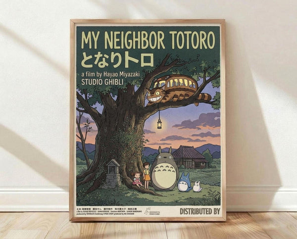 May include: Framed Studio Ghibli poster print leaning against white wall on light wood floor. Features My Neighbor Totoro artwork with large tree, cat bus in branches with glowing windows, two children and Totoro characters beneath. Soft twilight colors in purple, green, and cream. Japanese text visible. Natural wood frame. Warm lighting creates gentle shadows on textured wall.