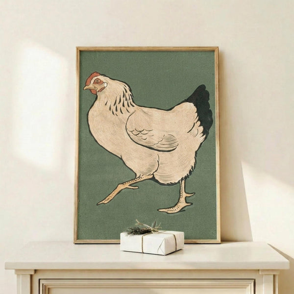 May include: Vintage Japanese woodblock print of a white hen with black tail feathers and red comb on sage green background, displayed in thin wooden frame on light wood shelf next to small white wrapped gift with natural twine and dried sprig accent against cream wall