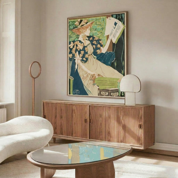 May include: Art Nouveau poster in wooden frame on white wall above mid-century walnut credenza. Colorful vintage advertisement shows woman in flowing dress with orange hair holding papers. Modern living room with white curved chair, glass coffee table, and contemporary lighting. Poster features green, blue, and cream tones in decorative Art Nouveau style.