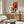 May include: Japanese-inspired poster print featuring red octopus with curling tentacles against cream background with blue wave design and Asian calligraphy, displayed above mid-century modern walnut credenza in minimalist living room with white curved chair, brass floor lamp, and oval glass coffee table