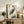 May include: Japanese woodblock print of a grey heron with long orange beak standing among marsh grasses, displayed in light wood frame on rustic wooden sideboard alongside fern plant, books, and ceramic vase in neutral-toned living room setting