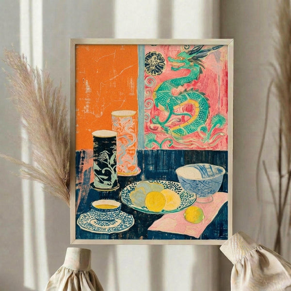 May include: Framed colorful still life artwork displayed on white fabric backdrop with dried pampas grass. The vibrant print features Asian-inspired dragon motif in green and pink, orange geometric sections, and blue table surface with decorative bowls, lemons, teacup, and ornate vases. Bright coral, navy, yellow, and turquoise colors create bold contrast in this artistic room mockup scene.