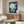 May include: Japanese-style artwork print showing white cranes flying against deep blue sky with large pale moon, displayed above mid-century walnut credenza in modern living room with cream curved chair, oval glass coffee table, and contemporary lighting fixtures on neutral walls