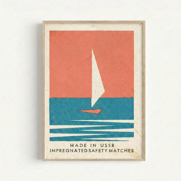 Framed vintage-style poster featuring a minimalist sailboat design with white sail on coral and teal blue background. The boat sits on stylized blue waves with text reading "MADE IN USSR IMPREGNATED SAFETY MATCHES" below. Natural wood frame against white wall with cream matting and slightly textured paper appearance.