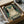 May include: Vintage-style poster featuring a tabby cat wearing black headphones on a teal green distressed background. The design has cream-colored text at top and bottom with musical note decorations. The poster is displayed in a cardboard shipping box with tissue paper packaging, surrounded by white fabric on a light surface.