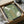May include: Green vintage-style poster with Japanese text and white illustrated squid and abalone shell, displayed in black frame inside cardboard shipping box with protective wrapping. Wooden dowels visible alongside for hanging. Muted sage green background with cream-colored sea creatures and golden Japanese characters in traditional calligraphy style.