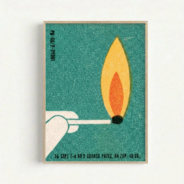 Vintage Polish matchbox label poster print in light wood frame against white wall. Features minimalist illustration of white hand lighting a match with yellow and orange flame on teal textured background. Black Polish text appears at top and bottom of design. Mid-century modern graphic design style with bold geometric shapes and limited color palette.