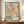 May include: Framed poster with abstract colorful design featuring flowing curves in turquoise and pink, scattered dots and circles in various sizes and colors including black, coral, yellow, and green, displayed on wooden sideboard next to white ceramic vase and stacked books in elegant room with crown molding and cream walls.