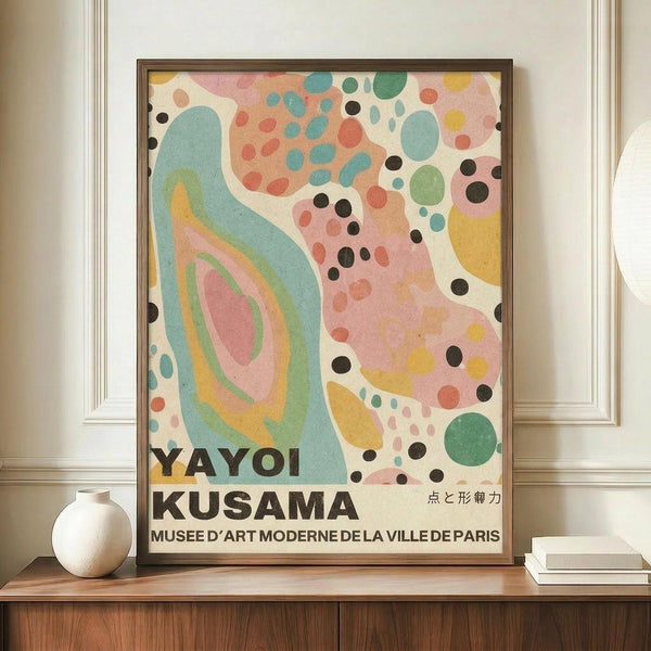 May include: Framed poster with abstract colorful design featuring flowing curves in turquoise and pink, scattered dots and circles in various sizes and colors including black, coral, yellow, and green, displayed on wooden sideboard next to white ceramic vase and stacked books in elegant room with crown molding and cream walls.