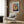 May include: Colorful fish poster with polka dot pattern in Yayoi Kusama style, featuring vibrant orange and blue sections with large eye detail, displayed in cream frame on wood-paneled wall. Modern reading chair with geometric pillow sits below artwork next to brass floor lamp and side table with open book.