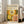 May include: Framed art print leaning against white wall next to beige sofa in bright living room. Poster features colorful dotted circular patterns in yellow, orange, and white on dark background with Japanese text and "JAPAN 1987" at top. Light wood frame, hardwood floors visible.
