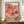 May include: Framed poster with colorful abstract polka dot pattern in coral, pink, orange, and teal tones displayed on wooden sideboard. White ceramic vase and stacked books sit nearby. The artwork features organic spotted shapes with Japanese text at top and "1981" at bottom. Warm neutral wall and elegant molding visible in background.