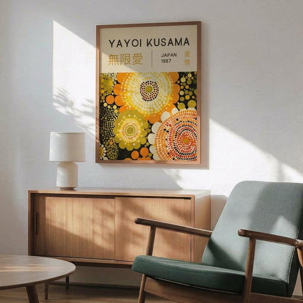 May include: Framed art poster with colorful circular dot patterns in yellow, orange, and green tones displayed on white wall above wooden sideboard with lamp, beside mid-century modern teal upholstered chair with wooden arms in bright, naturally lit room with contemporary furniture