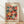 May include: Framed poster featuring colorful illustrated mushrooms in various sizes and patterns against a dark background. The artwork shows polka-dotted mushrooms in red, orange, pink, green, and yellow tones. Text reads "YAYOI KUSAMA" in red letters with Japanese characters and "1988" at bottom. Natural wood frame sits on light wooden floor against white wall with soft window light shadows.