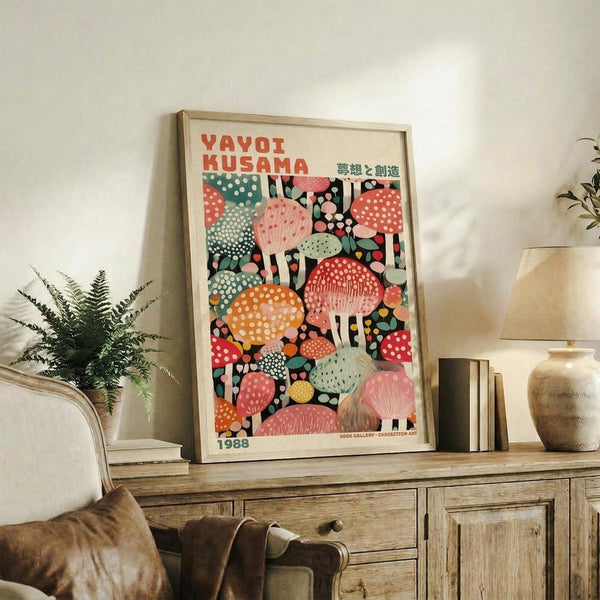 May include: Colorful mushroom art poster in light wood frame displayed on rustic wooden sideboard in modern living room. Vibrant illustration features whimsical spotted mushrooms in pink, orange, teal, and red against dark background. Room styled with fern plant, ceramic vases, books, and neutral furniture creating warm, contemporary home decor setting.