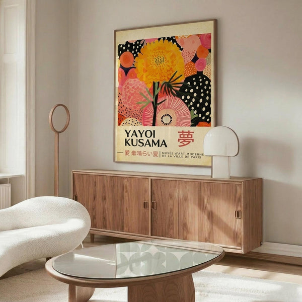 May include: Framed colorful abstract floral poster featuring large yellow dahlia, pink and orange circular patterns, and black polka dot elements, displayed above mid-century walnut credenza in minimalist living room with white curved chair, glass oval coffee table, and brass floor lamp