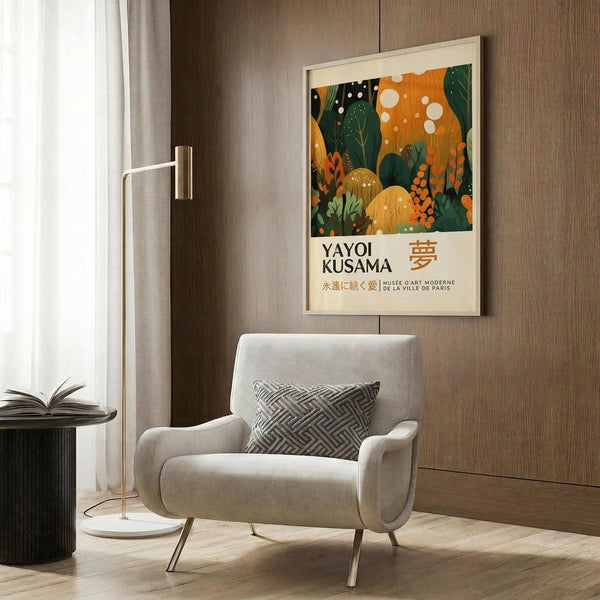 May include: Colorful art poster featuring abstract botanical design in orange, green, and cream tones with polka dots and organic shapes, displayed in light wood frame on wood-paneled wall above cream upholstered armchair with geometric patterned pillow, brass floor lamp and dark round side table with open book nearby