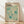 May include: Framed vintage-style exhibition poster featuring abstract organic shapes in turquoise and teal against cream background, displayed on light wood floors against white wall with natural window light casting shadows. Wooden frame surrounds artwork with bold black text at top, Japanese characters, scattered polka dot patterns, and flowing botanical-inspired forms throughout the composition.