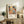 May include: Framed poster with colorful abstract floral design featuring large blooms in orange, yellow, and pink with polka dot patterns in blues and earth tones, displayed on rustic wooden console table alongside fern plant, ceramic vase, and books in neutral-toned living room setting