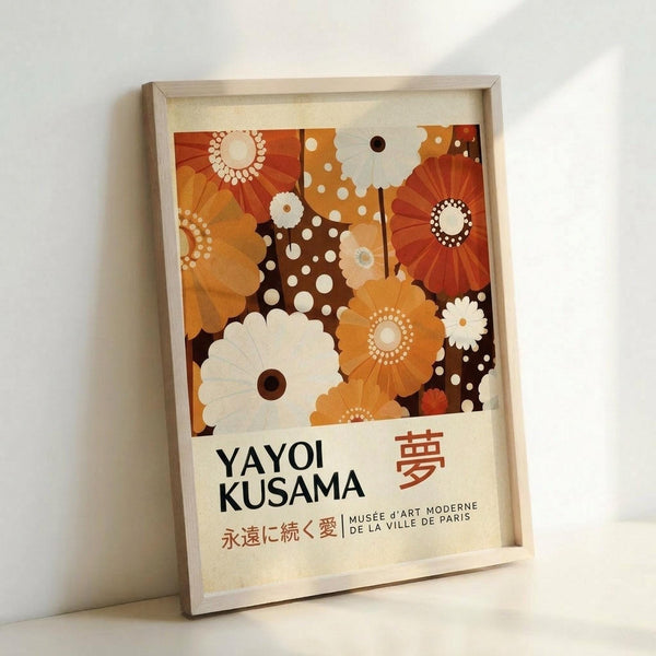 May include: Framed poster with vibrant orange, brown and cream floral pattern featuring stylized flowers, dots and radiating designs in mid-century modern style. Light wooden frame against white wall, showing museum exhibition text with "YAYOI KUSAMA" and Japanese characters, referencing Musée d'Art Moderne de la Ville de Paris.