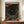 May include: Framed art print with abstract cosmic design featuring swirling patterns in black, orange, red and blue tones with scattered dots and celestial elements, displayed on wooden sideboard next to white ceramic vase and stacked books against cream wall with white trim