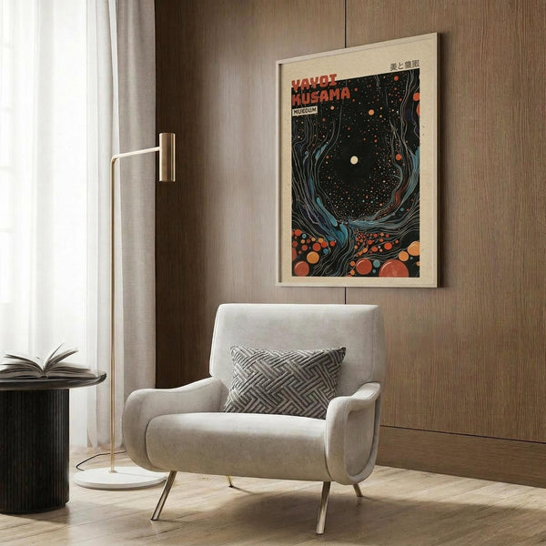 May include: Colorful poster with cosmic, swirling design featuring orange and red dots against dark background, displayed in light wood frame on wood-paneled wall. Modern reading corner with cream upholstered armchair, geometric patterned pillow, brass floor lamp, and dark round side table with open book. Warm neutral tones throughout contemporary interior space.