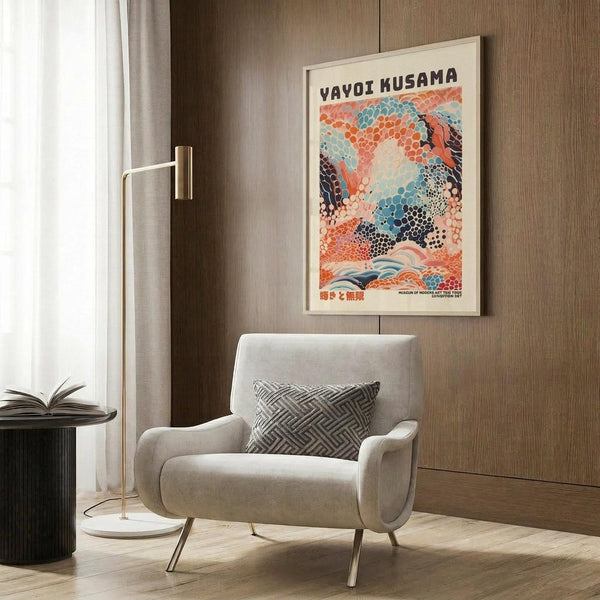 May include: Colorful abstract art poster with dotted patterns in coral, blue, and cream tones displayed in modern living room with beige armchair, brass floor lamp, and wood panel wall. Framed artwork features flowing organic shapes and polka dot motifs in Japanese-inspired style.